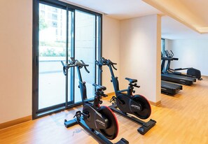 A gym with stationary bikes, large windows, and a wooden floor. - Waterfront Apt w/ Pool, Gym & Direct Beach Access (Sharjah)