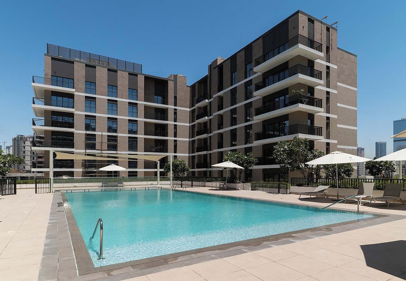 Un bâtiment moderne doté d’une piscine, d’un espace extérieur aménagé et offrant une vue sur un ciel dégagé.