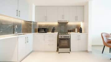 A modern kitchen with white cabinets, a stainless steel stove, and a microwave.