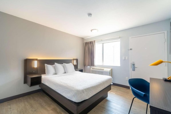 A modern hotel room with a large bed, bedside tables, a desk, and a chair.