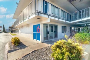 A modern hotel with a prominent '6' sign, a covered entrance, and a balcony. - 1 Queen Bed|Mobility|RI Shwr|Micfridg (Del Rio)