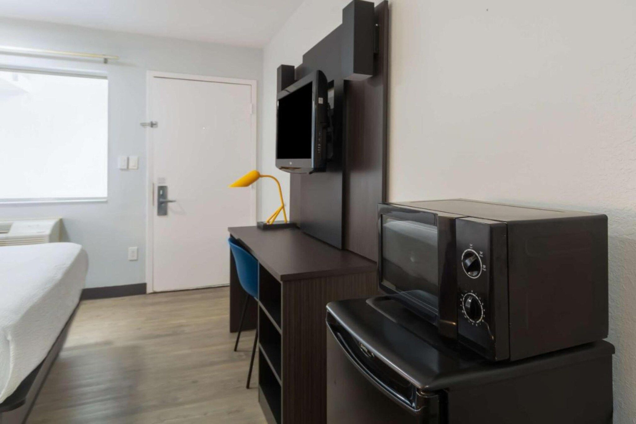 A hotel room with a bed, a desk, a television, and a microwave.