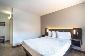 Et hotelværelse med en stor seng, to sengeborde og et natbord med en lampe.