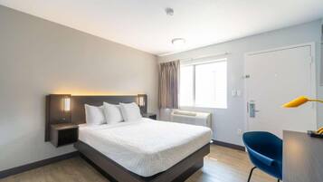 Habitación de hotel moderna con una cama grande, mesitas de noche, un escritorio y una silla.
