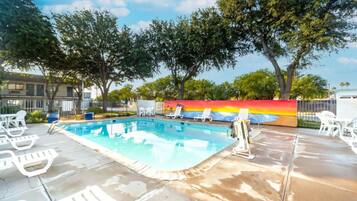 A swimming pool with lounge chairs and a colorful mural in the background.