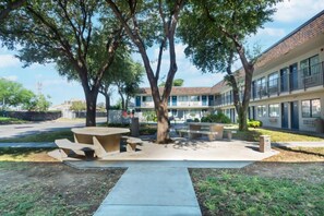 A courtyard with a picnic table and benches, surrounded by trees and a building with multiple windows.
