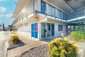 Et moderne hotel med et tydeligt skilt med '6', en overdækket indgang og en balkon.