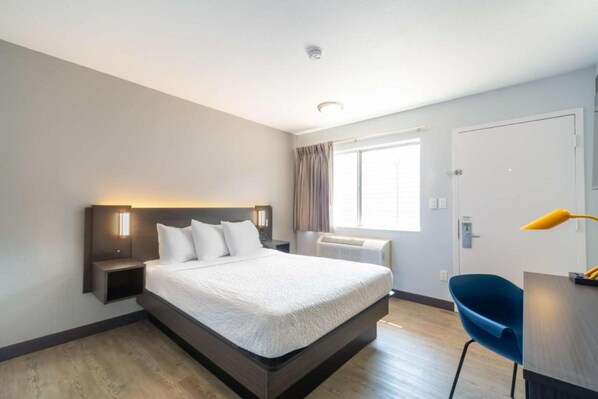 A modern hotel room with a large bed, bedside tables, a desk, and a chair. - 1 Queen Bed | Non-Smoking (Del Rio)