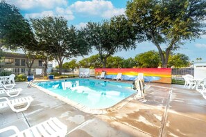 A swimming pool with lounge chairs and a colorful mural in the background. - 1 Queen Bed | Non-Smoking (Del Rio)