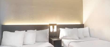 A hotel room with two beds, a nightstand, and a wall-mounted light fixture.