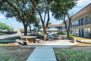A courtyard with a picnic table and benches, surrounded by trees and a building with multiple windows. - 2 Full Beds | Nsmk, Micfridge (Del Rio)