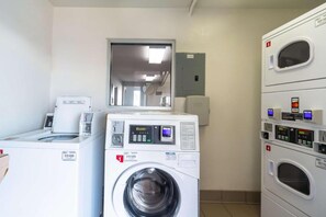 A laundry room with multiple washing machines and dryers, a control panel, and a door leading to another room. - 2 Full Beds | Non-Smoking (Del Rio)
