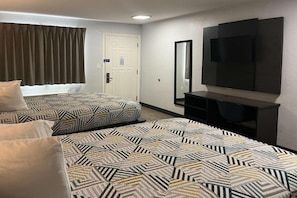 Een hotelkamer met twee bedden, een televisie, een bureau en een deur.