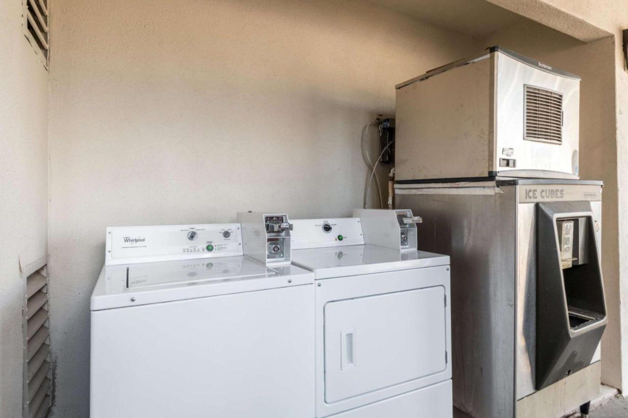 A laundry area with two Whirlpool washers and a stainless steel ice cube dispenser.