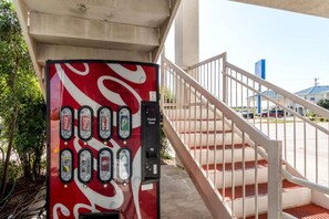 Een Coca-Cola automaat onder een brug, met een trap die naar een parkeerplaats leidt.