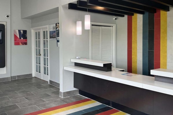 A reception area with a modern design, featuring a reception desk, a glass door entrance, and a colorful wall. - 3 Queen Beds | Non-Smoking (Seguin)