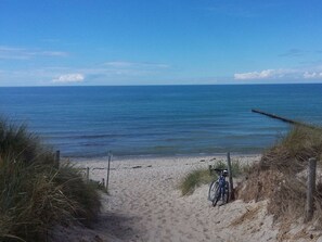 A sandy beach with a bicycle parked on the right, leading to the water. - Holiday Home With 5 Bedrooms (Ribnitz-Damgarten)