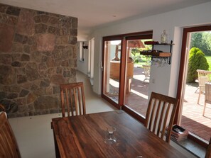 A dining area with a stone wall, wooden table, and chairs. - Holiday Home With 5 Bedrooms (Ribnitz-Damgarten)