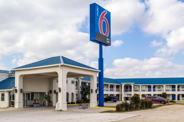 A motel with a prominent '6' sign, a covered parking area, and a row of rooms with balconies. - 2 Queen Beds | Non-Smoking (Seguin)
