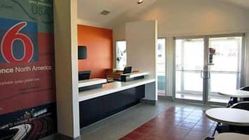 A reception area with a counter, a large poster on the wall, and a glass door leading outside.