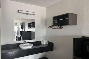 Een badkamer met een witte wastafel, een spiegel en een zwart aanrecht.