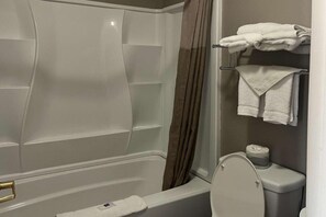 Een badkamer met een bad, toilet en handdoekrek.