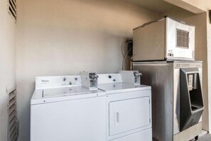 Een wasruimte met twee Whirlpool wasmachines en een ijsblokjesdispenser van roestvrij staal.