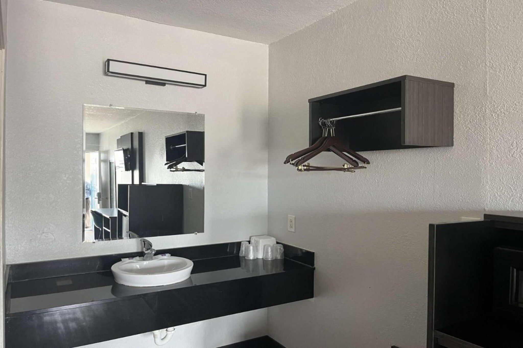 Un baño con un lavabo blanco, un espejo y una encimera negra.