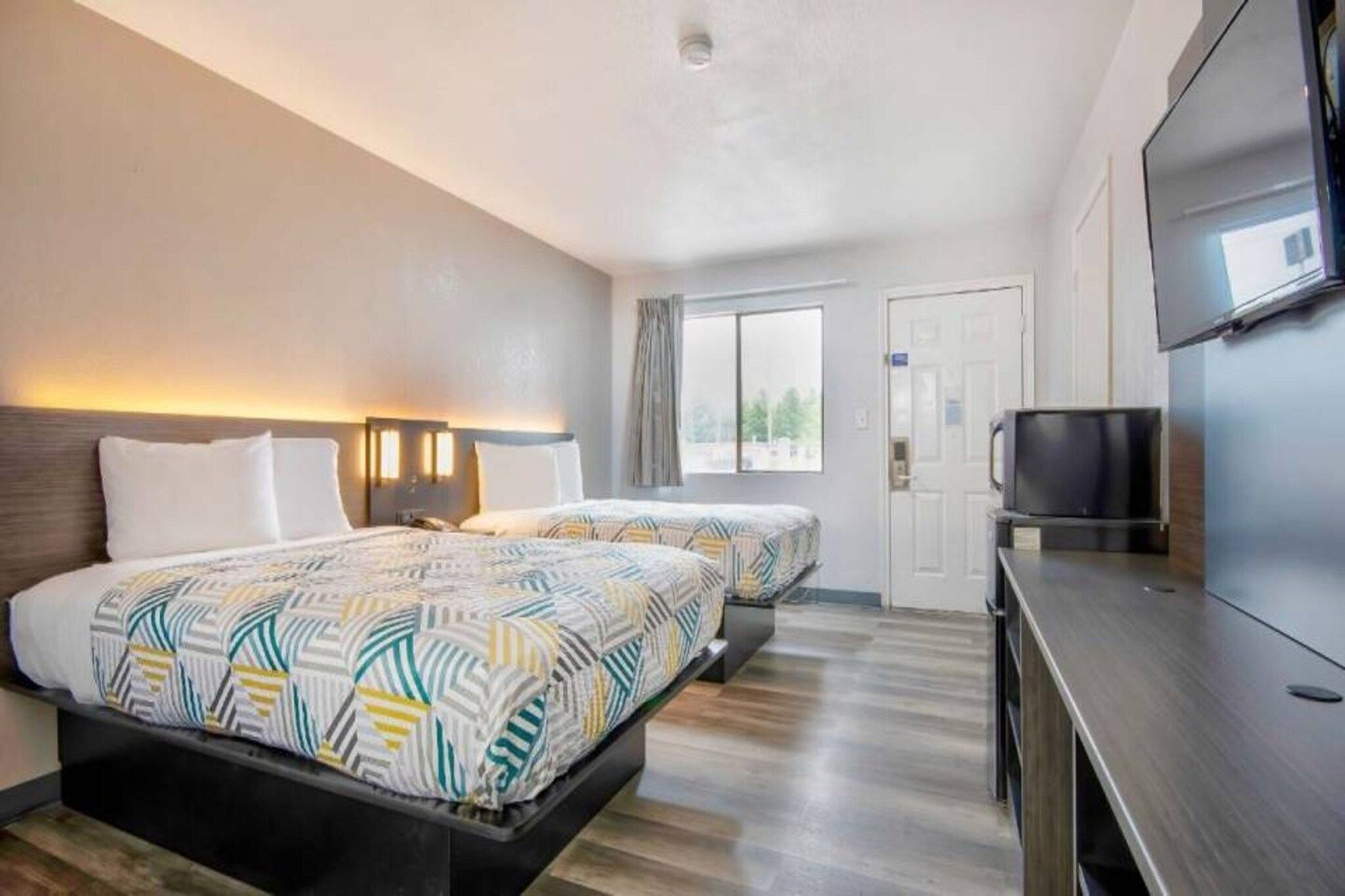 A hotel room with two beds, a TV, and a window.