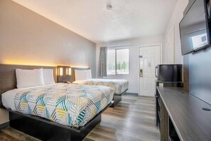 Habitació d'hotel amb dos llits, televisió i finestra.
