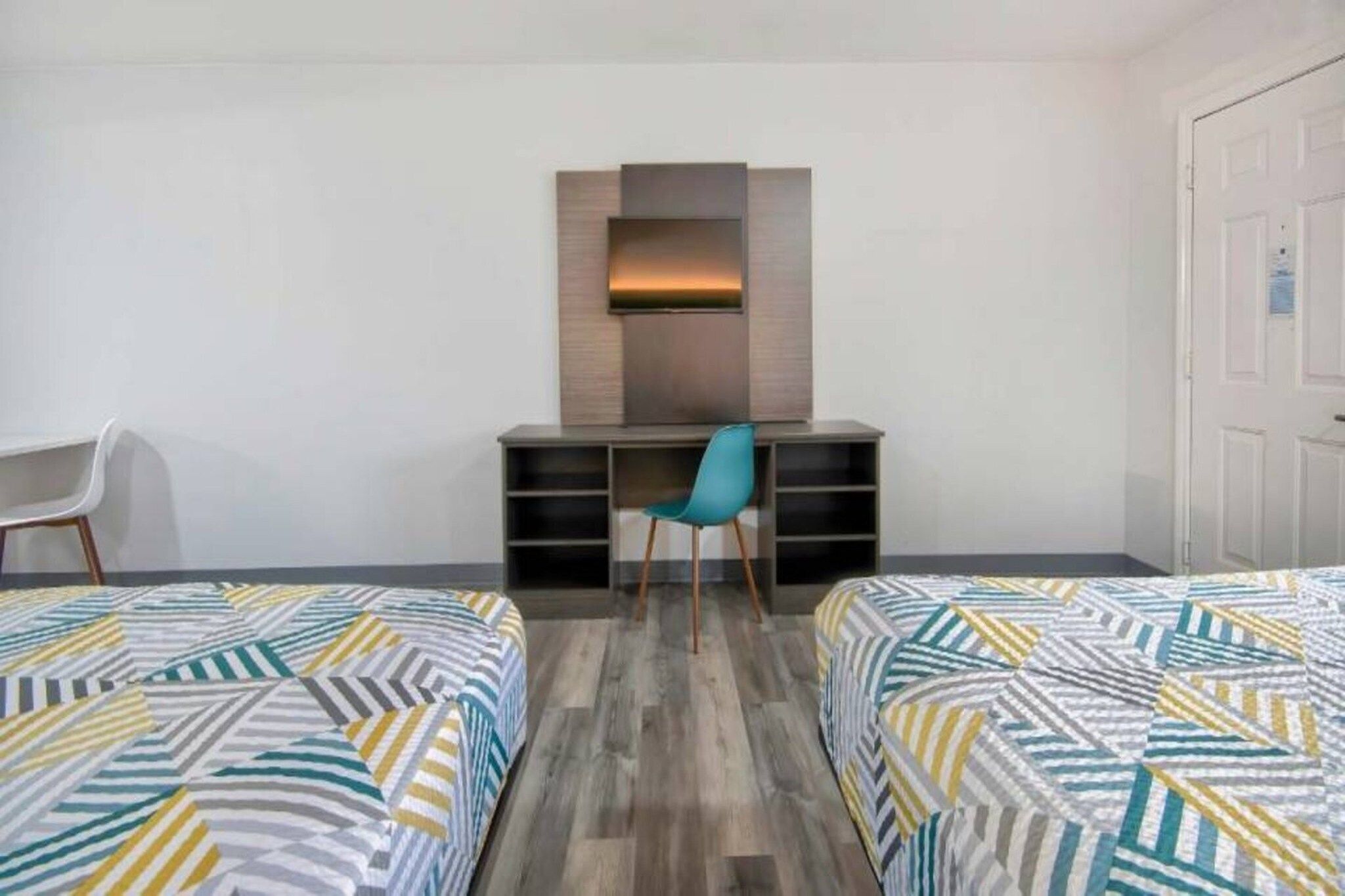 A hotel room with two beds, a desk, and a chair.