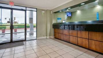 A reception area with a glass door entrance, a reception desk, and a television mounted on the wall.