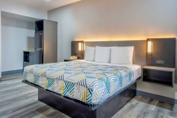 Une chambre d’hôtel moderne avec un grand lit, des tables de chevet, une armoire et un téléviseur intégré.