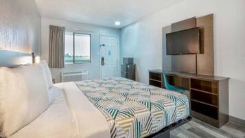 Ein Hotelzimmer mit einem Bett, einem Schreibtisch, einem Stuhl, einem Fernseher und einem Fenster.