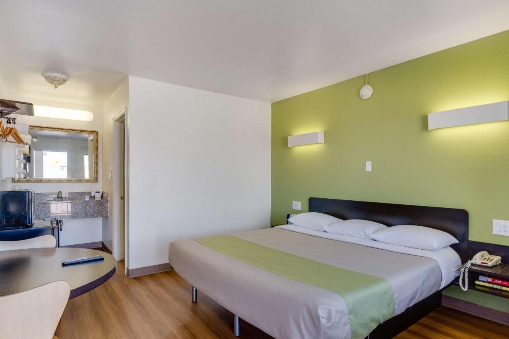 Una habitación de hotel con cama, mesita de noche y escritorio con silla.
