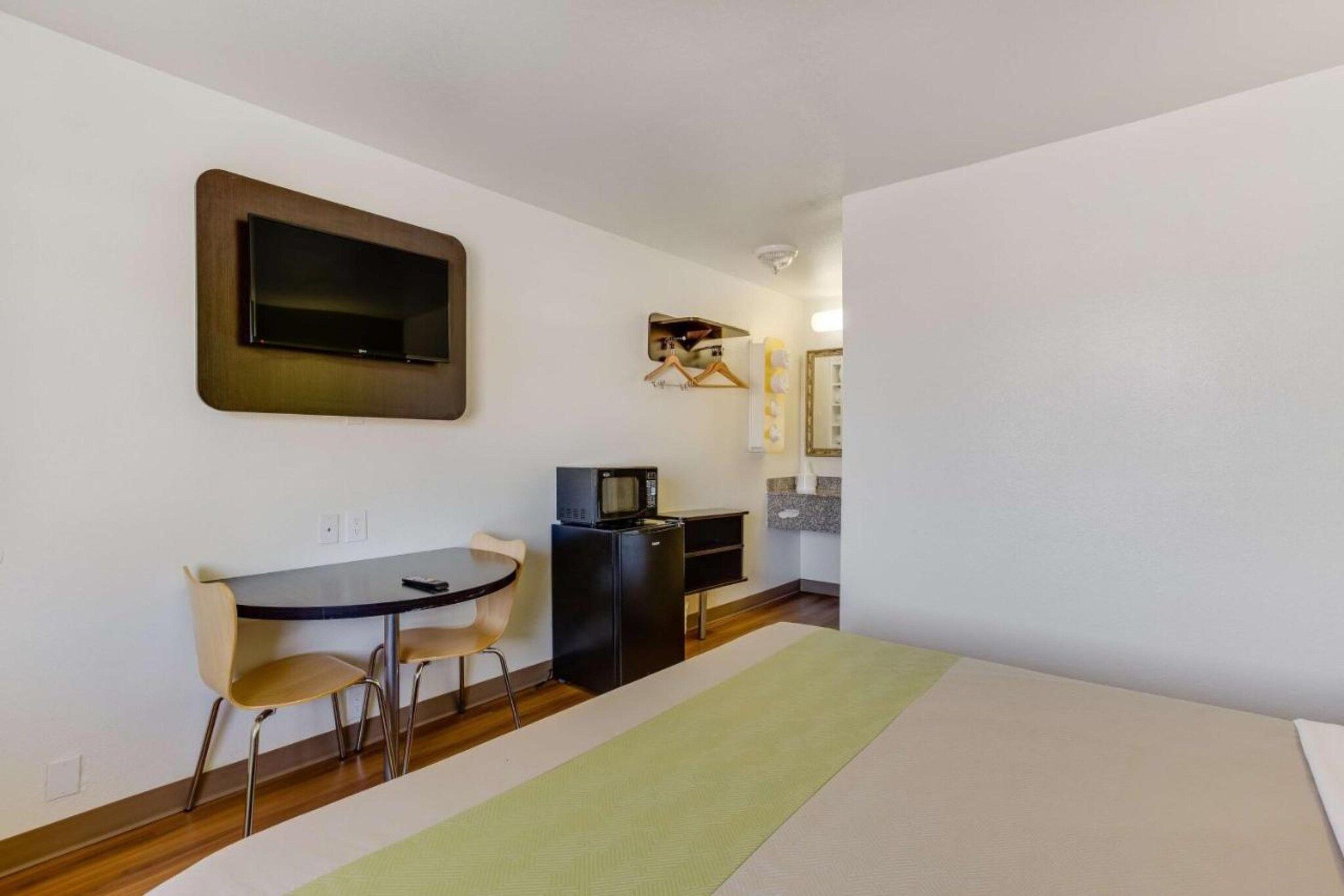 A compact room with a dining table, chairs, a television, a microwave, and a refrigerator.