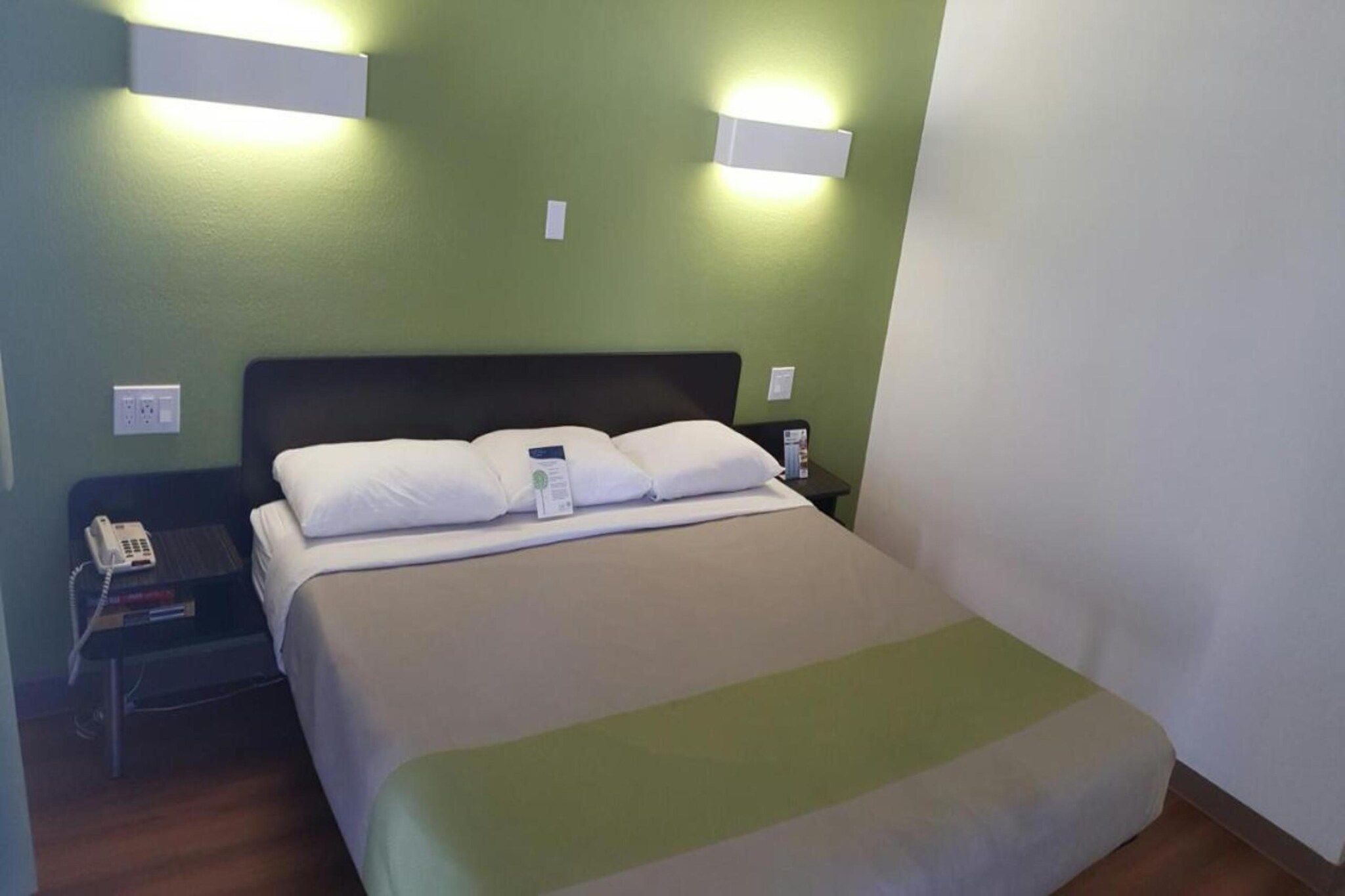 A hotel room with a bed, bedside table, and a phone.