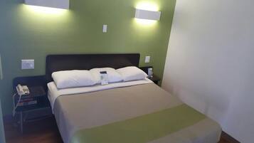 A hotel room with a bed, bedside table, and a phone.