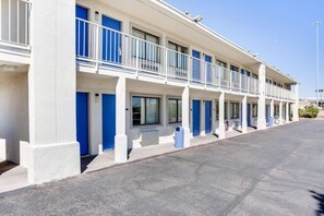 Een motel met een rij kamers, elk met een balkon en een blauwe deur.