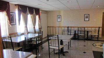 A dining area with tables and chairs, a tiled floor, and a patterned wall.