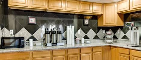 A kitchen with wooden cabinets, a microwave, and a coffee machine.