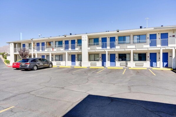 A motel with a parking lot, multiple rooms with blue doors, and a two-story structure. - 2 FULL BEDS | SMOKING (El Paso TX)