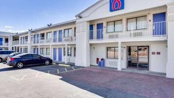 A motel with a '6' sign, multiple balconies, a parking area, and a lobby entrance.