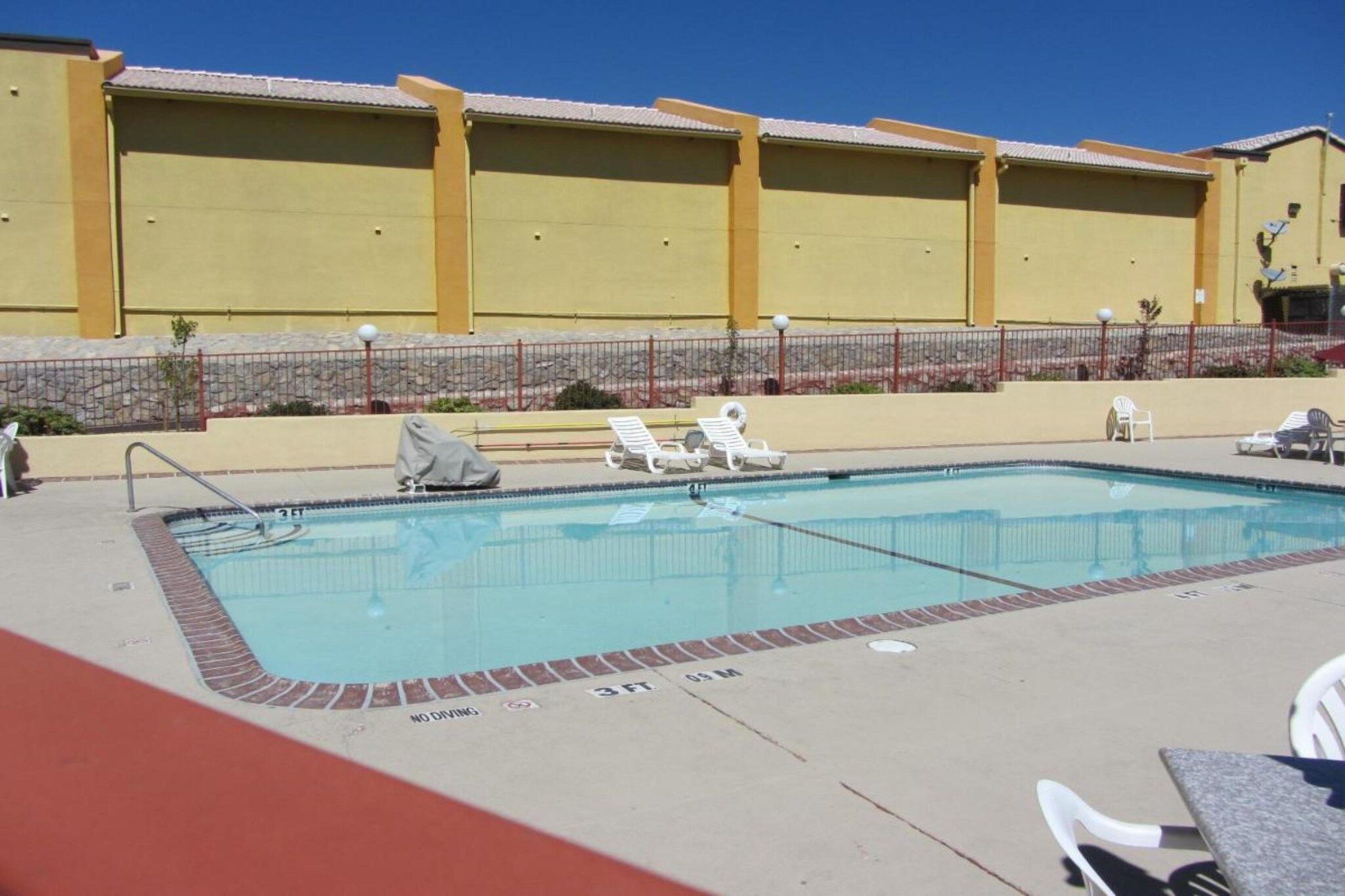 A swimming pool with lounge chairs and a no diving sign.