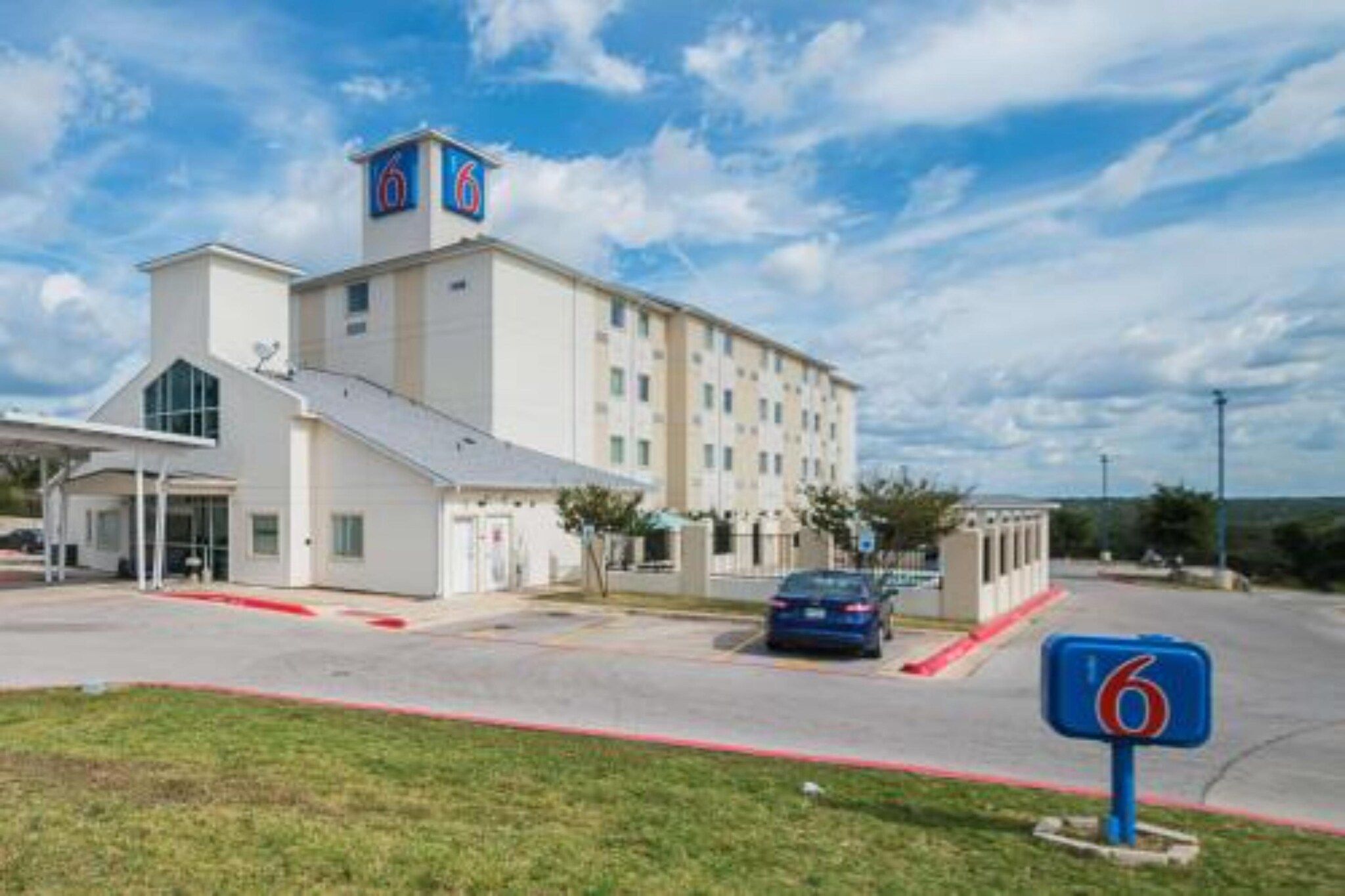 Un hôtel à plusieurs étages, reconnaissable à son grand panneau lumineux en forme de « 6 », doté d’une entrée abritée et d’un espace de stationnement.