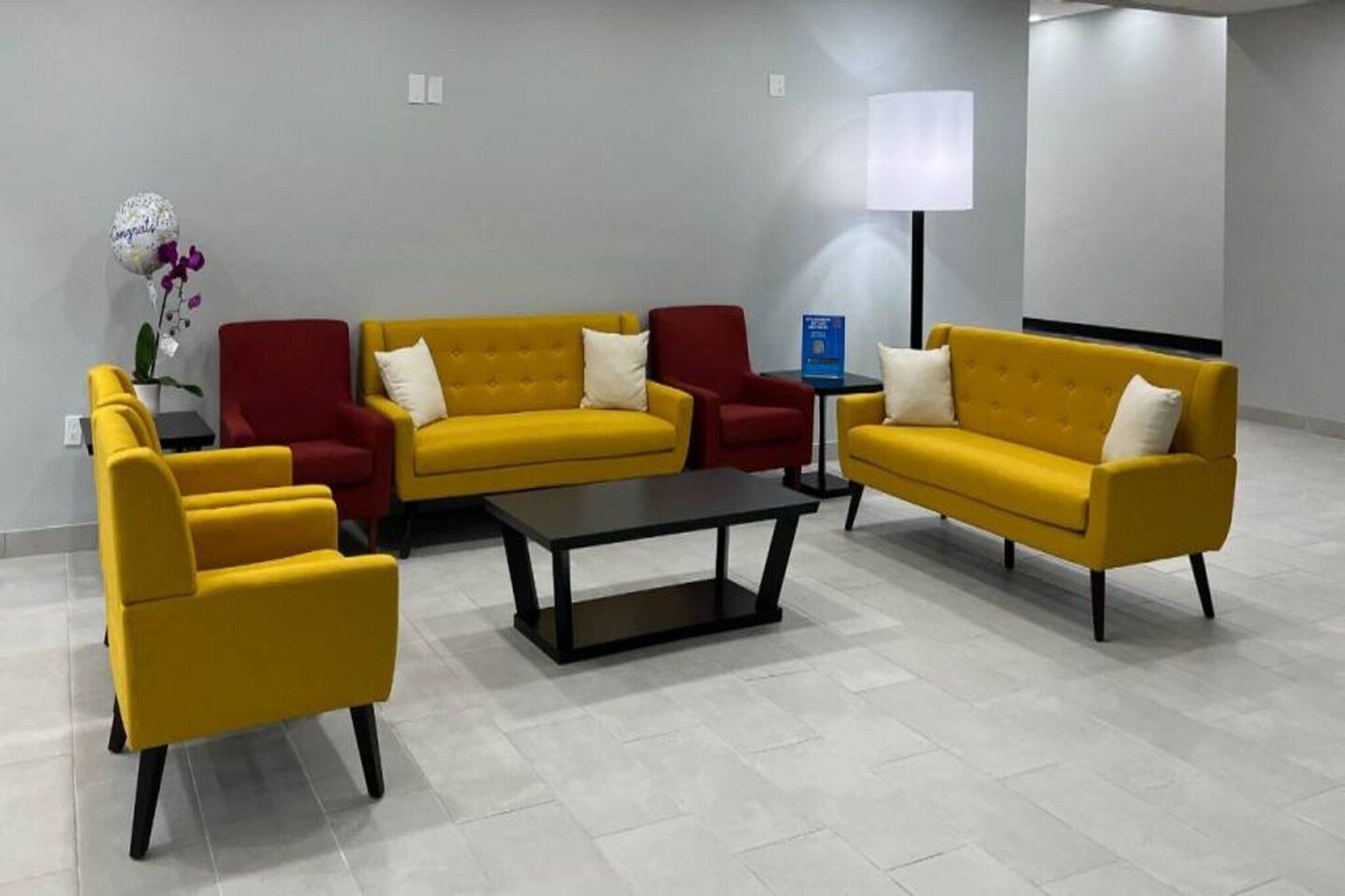 A modern living room with yellow sofas, red armchairs, and a black coffee table.