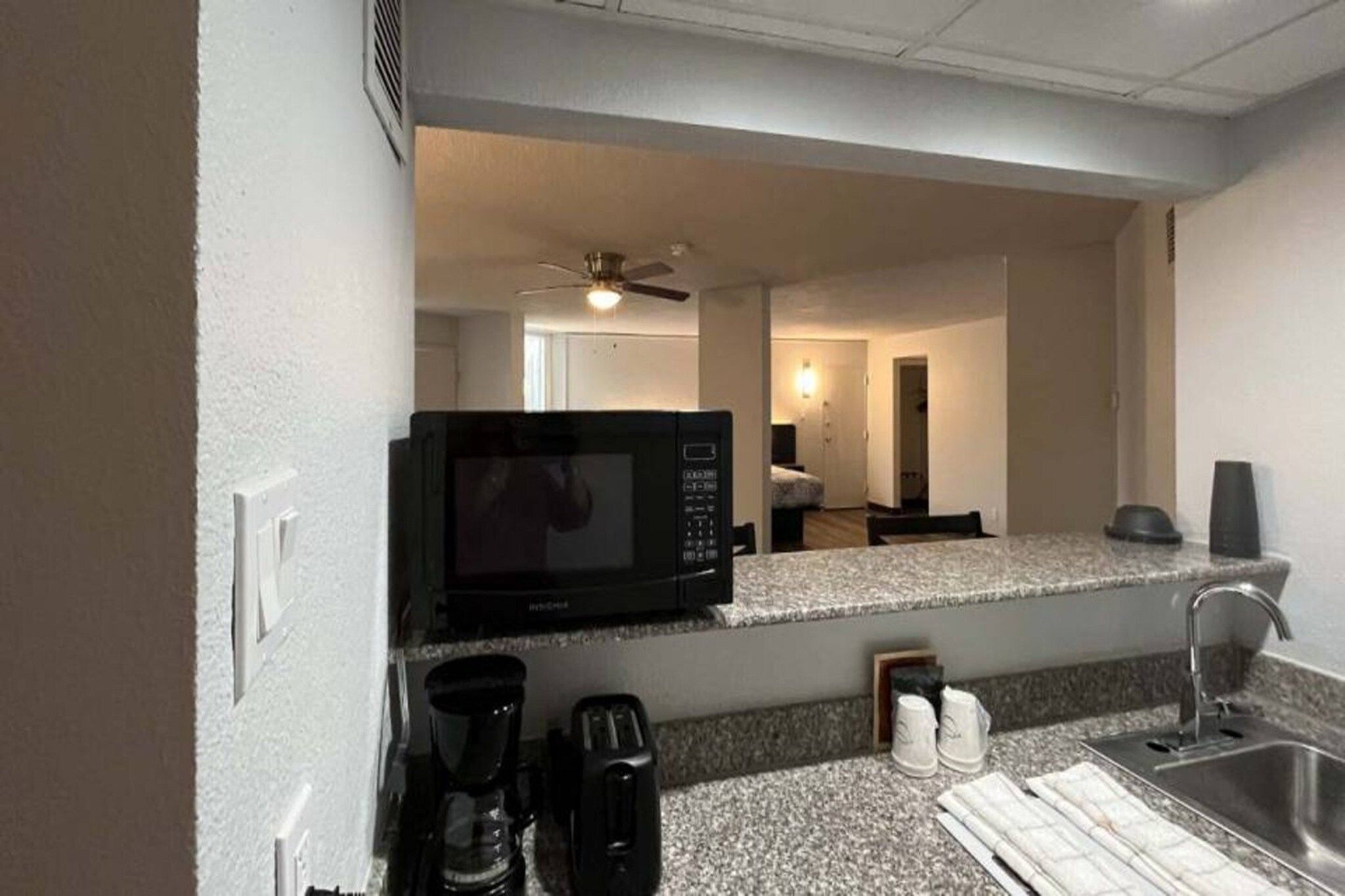 A compact kitchenette with a microwave, coffee maker, and sink.