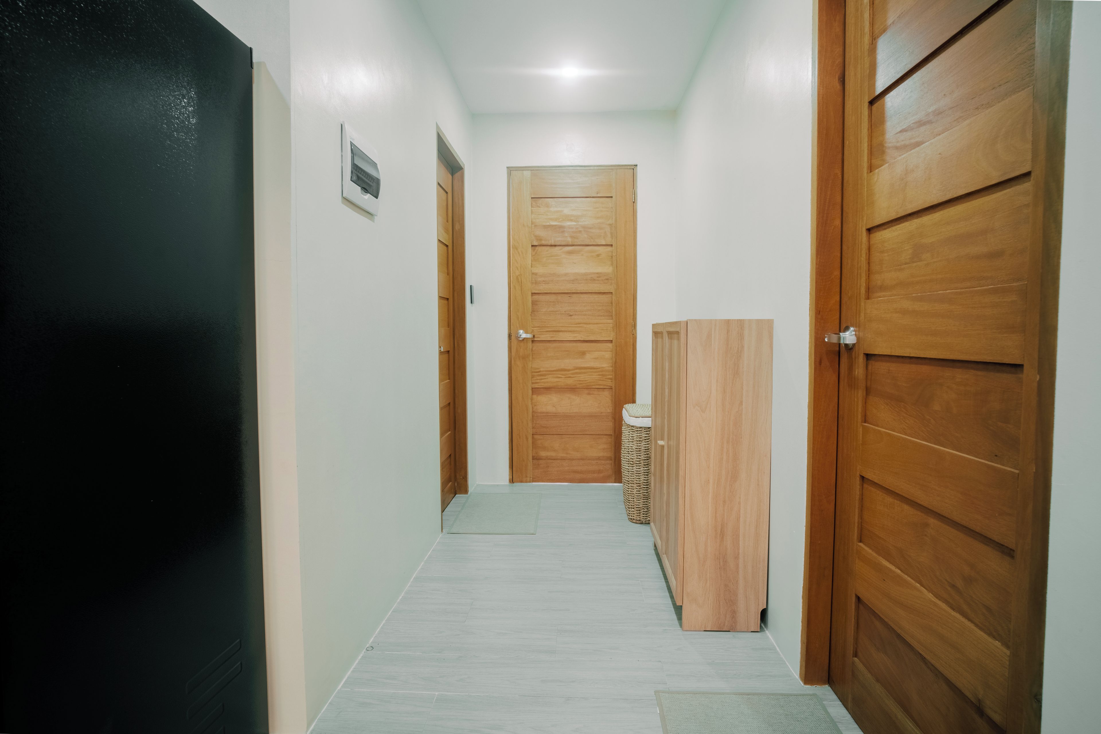 A hallway with wooden doors, a trash bin, and a mat on the floor.