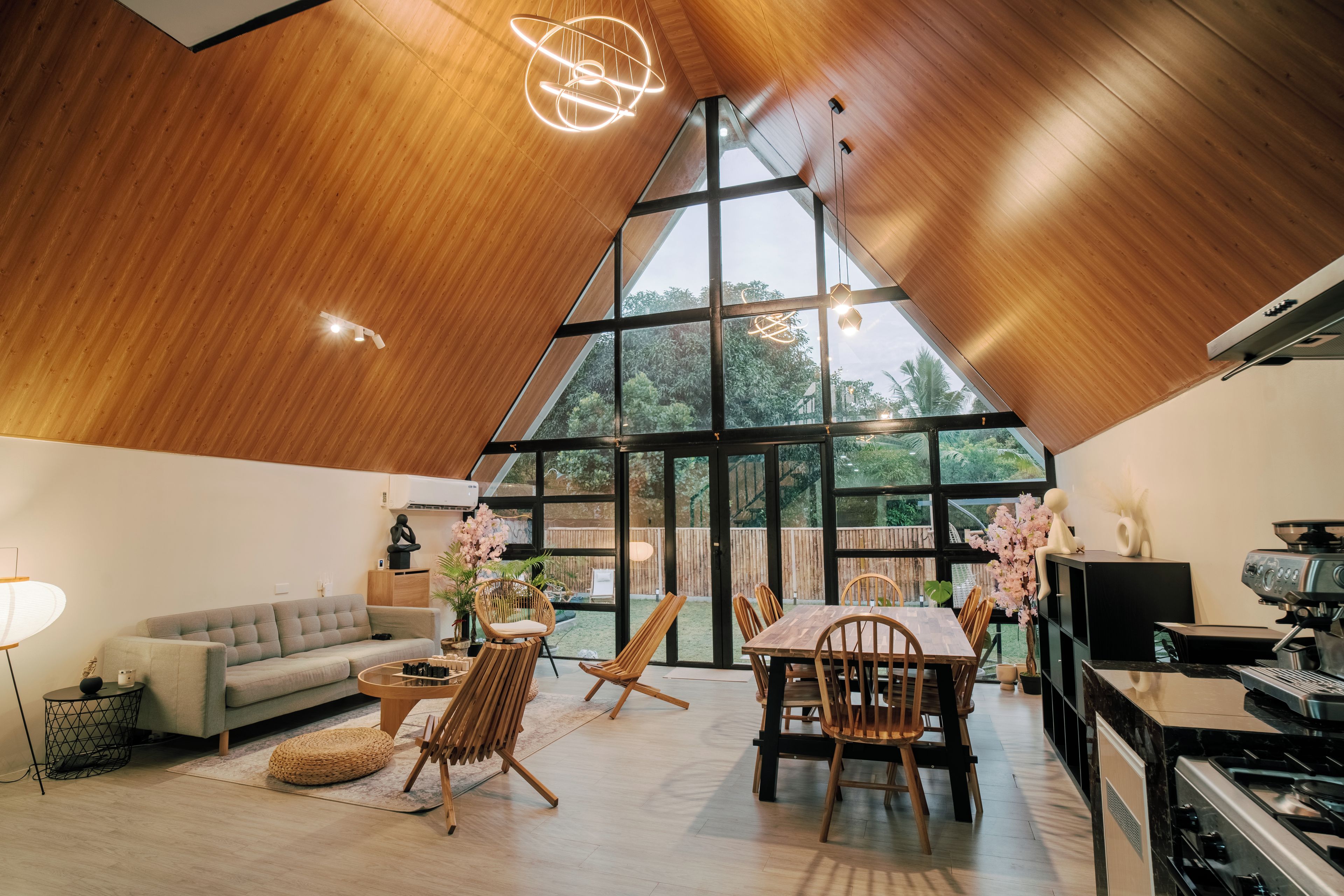Interior moderno com teto alto, área de refeições e cozinha com fogão.