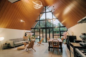 A modern interior with a high ceiling, a dining area, and a kitchen with a stove.